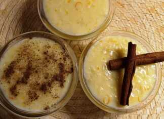 Μπολ γεμάτα με λευκό, κρεμώδες ρυζόγαλο, με πορτοκαλί ξύσμα και πιθανώς κομματάκια φρούτου στην επιφάνεια.