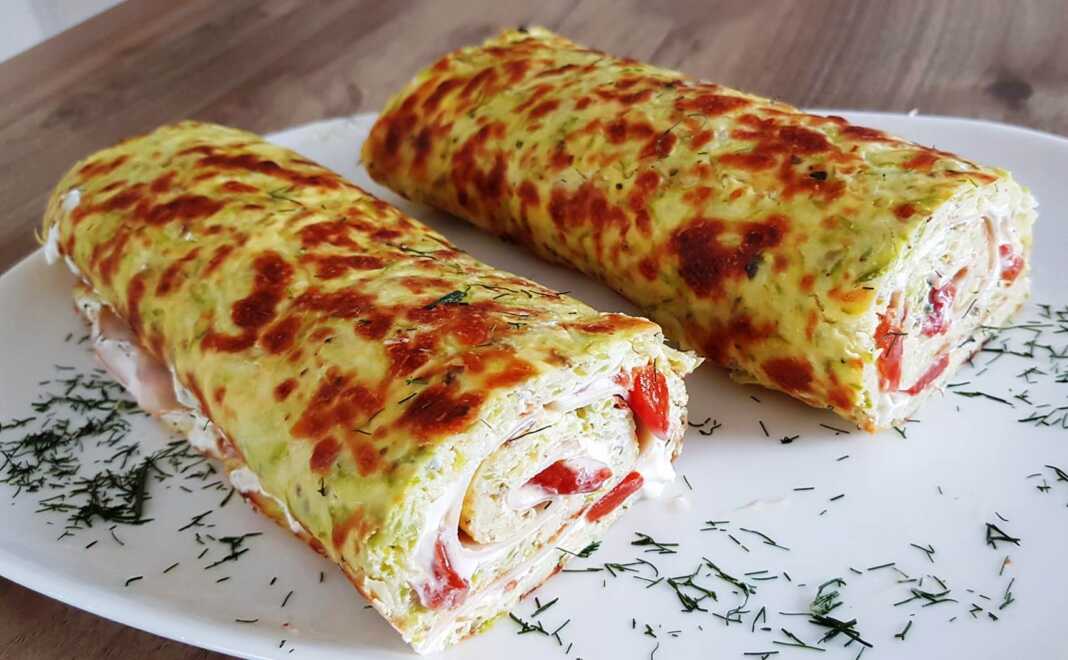 Κομμάτια από ψημένο ρολό κολοκυθιού, γεμιστό με τυρί ή άλλα υλικά, σερβιρισμένα σε πιάτο.