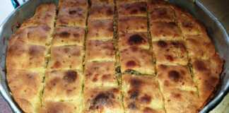 Μια ολόκληρη Σπανακοπρασόπιτα με σπιτικό φύλλο, χρυσαφένια και τραγανή, κομμένη σε κομμάτια, έτοιμη για σερβίρισμα.