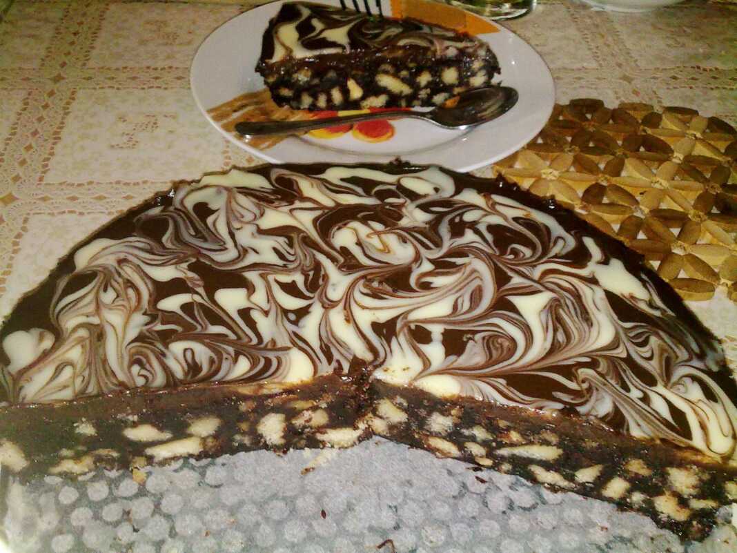 Ένα κομμένο κομμάτι μπισκοτογλυκού με στρώσεις μπισκότων, καρυδιών και σοκολάτας, καλυμμένο με λείο γλάσο σοκολάτας.