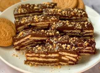 Στρώσεις από μπισκότα και σοκολατένια πουτίγκα σε ένα ορθογώνιο γλυκό ψυγείου πασπαλισμένο με φουντούκια