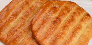 Δύο χρυσαφένια, στρογγυλά ψωμάκια με αυλάκια στην επιφάνεια και πασπαλισμένα με σουσάμι, σε ένα ταψί.