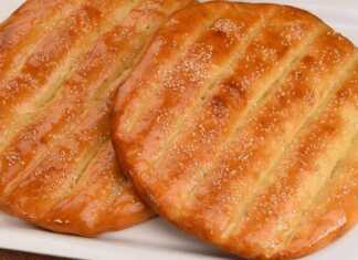 Δύο χρυσαφένια, στρογγυλά ψωμάκια με αυλάκια στην επιφάνεια και πασπαλισμένα με σουσάμι, σε ένα ταψί.