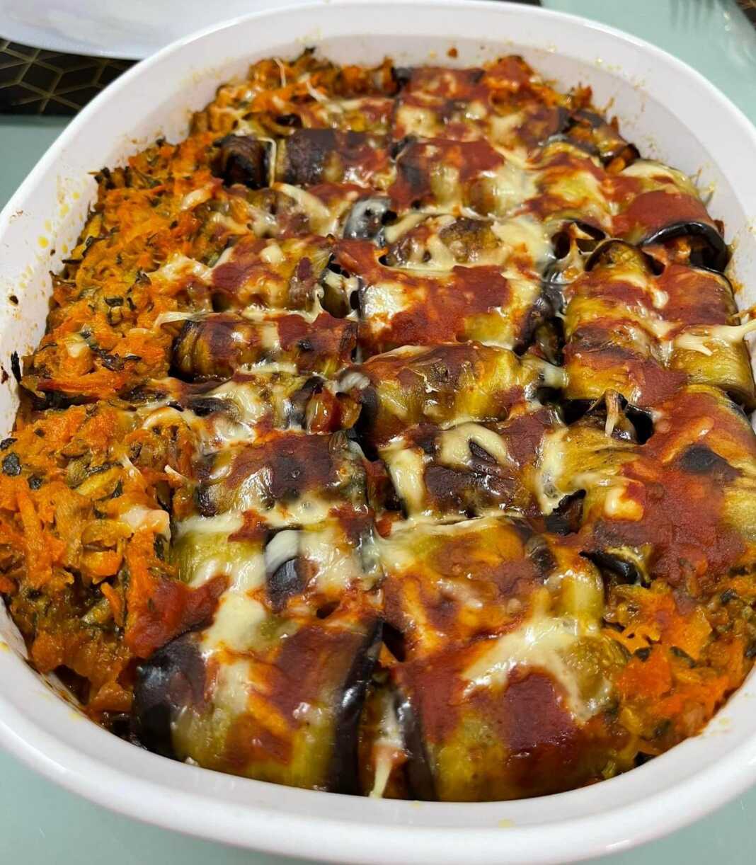 Ρολάκια μελιτζάνας ψημένα σε πυρέξ, με τυρί να έχει λιώσει από πάνω.