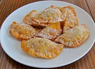 Μικρά χρυσαφένια τυροπιτάκια πασπαλισμένα με μπόλικη άχνη ζάχαρη και φρέσκο ξύσμα λεμονιού, σερβιρισμένα σε πιατέλα.