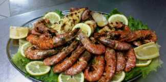 Πιάτο με ψητές γαρίδες και καλαμάρια, γαρνιρισμένα με μαϊντανό και φέτες λεμονιού, με ένα μπολ σάλτσα μουστάρδας δίπλα.