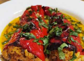 Ένα ταψί με κατακόκκινες γεμιστές πιπεριές Φλωρίνης, καλυμμένες με φέτες ντομάτας και φρέσκο μαϊντανό