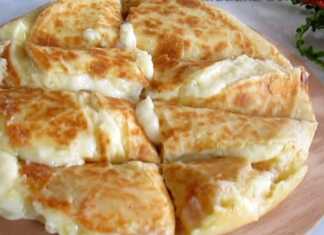 Μια σπιτική Κασερόπιτα με πατάτα σε ξύλο κοπής, κομμένη σε κομμάτια, έτοιμη για σερβίρισμα.