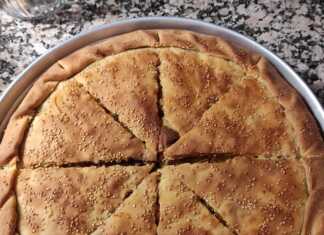 Παραδοσιακή κιμαδοπρασόπιτα με χρυσαφένιο χειροποίητο φύλλο, κομμένη σε μερίδες, πασπαλισμένη με σουσάμι.