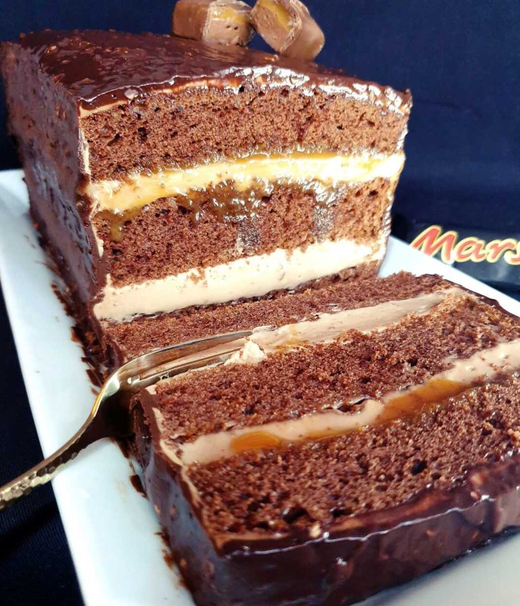 Τούρτα σοκολάτας με κρέμα και καραμέλα Mars σε κομμάτι, με εμφανείς τις τρεις στρώσεις παντεσπάνι και κρέμα.