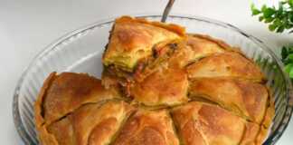 Μια χρυσαφένια μελιτζανόπιτα κομμένη σε κομμάτια, έτοιμη για σερβίρισμα.