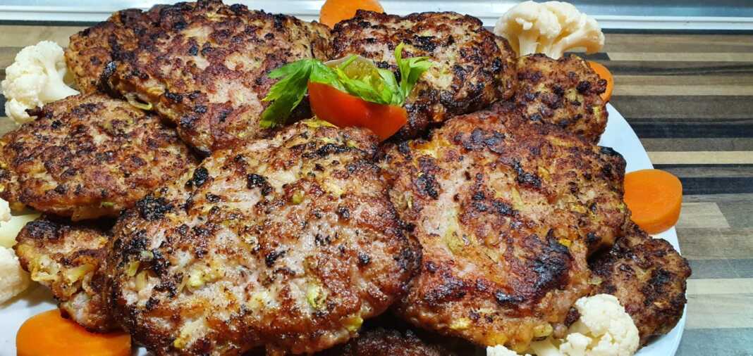 mpiftekiaLaxanika Τα ψημένα **Μπιφτέκια Φούρνου με Λαχανικά** σε πιάτο με συνοδευτικό