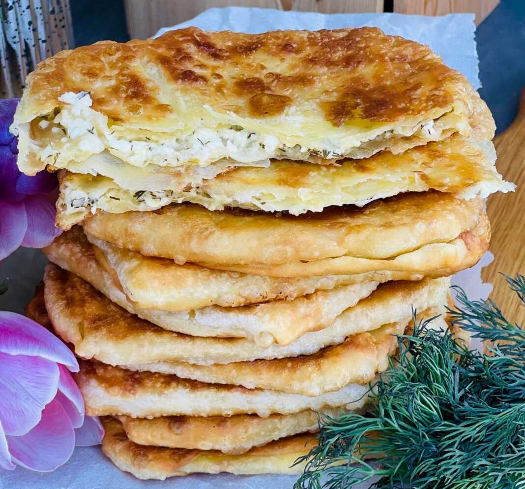 Τηγανητές πίτες διπλωμένες με τυρί και άνηθο, κομμένες στη μέση, με γέμιση να φαίνεται.