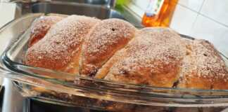 Ένα ολόκληρο, χρυσαφένιο κέικ πλεγμένο σε κοτσίδα, πασπαλισμένο με άχνη ζάχαρη, με τη γέμιση κακάο-καρύδας να φαίνεται διακριτικά.