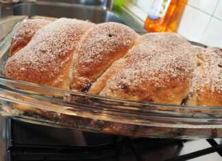 Ένα ολόκληρο, χρυσαφένιο κέικ πλεγμένο σε κοτσίδα, πασπαλισμένο με άχνη ζάχαρη, με τη γέμιση κακάο-καρύδας να φαίνεται διακριτικά.