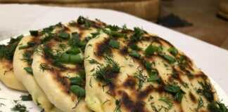 Μια στοίβα από χρυσαφένιες, τηγανισμένες πίτες με γέμιση τυριού, τοποθετημένες σε ξύλινη επιφάνεια.