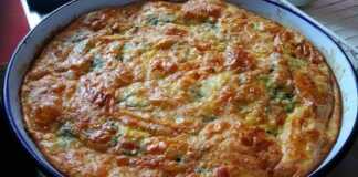 Ολόκληρη Πίτα με Χόρτα Κρατσανιστή, χρυσαφένια και κομμένη σε τετράγωνα, σε ξύλινη επιφάνεια