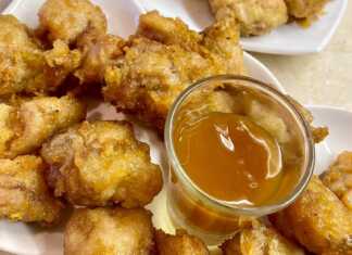 Ένα πιάτο με χρυσαφένιες, τραγανές μπουκιές κοτόπουλου περιχυμένες με γυαλιστερή καραμελωμένη σάλτσα, πασπαλισμένες με σουσάμι.