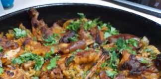 Ένα ταψί με ψητό κουνέλι πάνω από αφράτο ρύζι με μανιτάρια και κρεμμυδάκια.