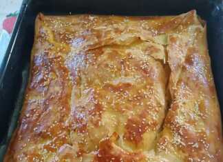 Μια χρυσή, τραγανή κρεατόπιτα με χειροποίητο φύλλο, κομμένη σε μεγάλα κομμάτια, όπου φαίνεται η πλούσια γέμιση από αρνίσιο κρέας και λαχανικά.