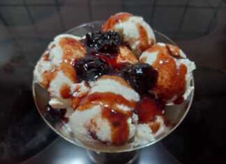 Ένα μπολ γεμάτο με κρεμώδες λευκό παγωτό γιαούρτι, με στροβιλισμούς από κόκκινο σιρόπι βύσσινο στην επιφάνεια.