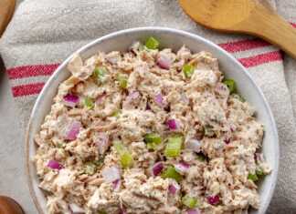 Μια πλούσια τονοσαλάτα με κομμάτια τόνου, κόκκινο κρεμμύδι και αγγούρι, ανακατεμένη με λευκό dressing γιαουρτιού σε ένα γυάλινο μπολ.