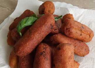 Μια στοίβα από χρυσαφένιους, τηγανητούς μελιτζανοκεφτέδες σε ένα πιάτο, γαρνιρισμένους με φρέσκα μυρωδικά.