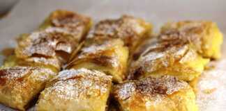 Μπουγάτσα με κρέμα, πασπαλισμένη με άχνη ζάχαρη και κανέλα, κομμένη σε κομμάτια.