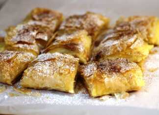 Μπουγάτσα με κρέμα, πασπαλισμένη με άχνη ζάχαρη και κανέλα, κομμένη σε κομμάτια.