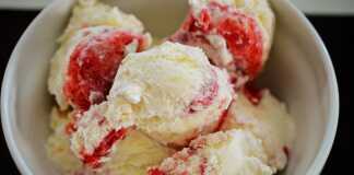 Ένα μπολ με λευκό παγωτό βανίλιας με κόκκινη σάλτσα φράουλας από πάνω.