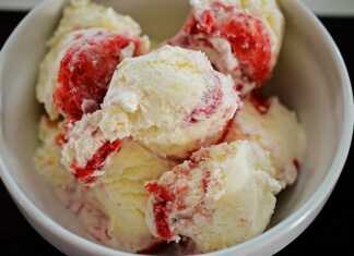 Ένα μπολ με λευκό παγωτό βανίλιας με κόκκινη σάλτσα φράουλας από πάνω.