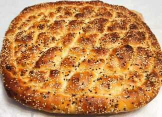 Ένα στρογγυλό χειροποίητο πολίτικο ψωμί πασπαλισμένο με σουσάμι με βαθιά χωρίσματα σε σχήμα ρόμβου και χρυσαφένιο χρώμα