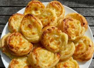 Μικρά ρολάκια σφολιάτας με χρυσαφένια κρούστα και λιωμένο τυρί που ξεχειλίζει, τοποθετημένα πάνω σε λαδόκολλα.