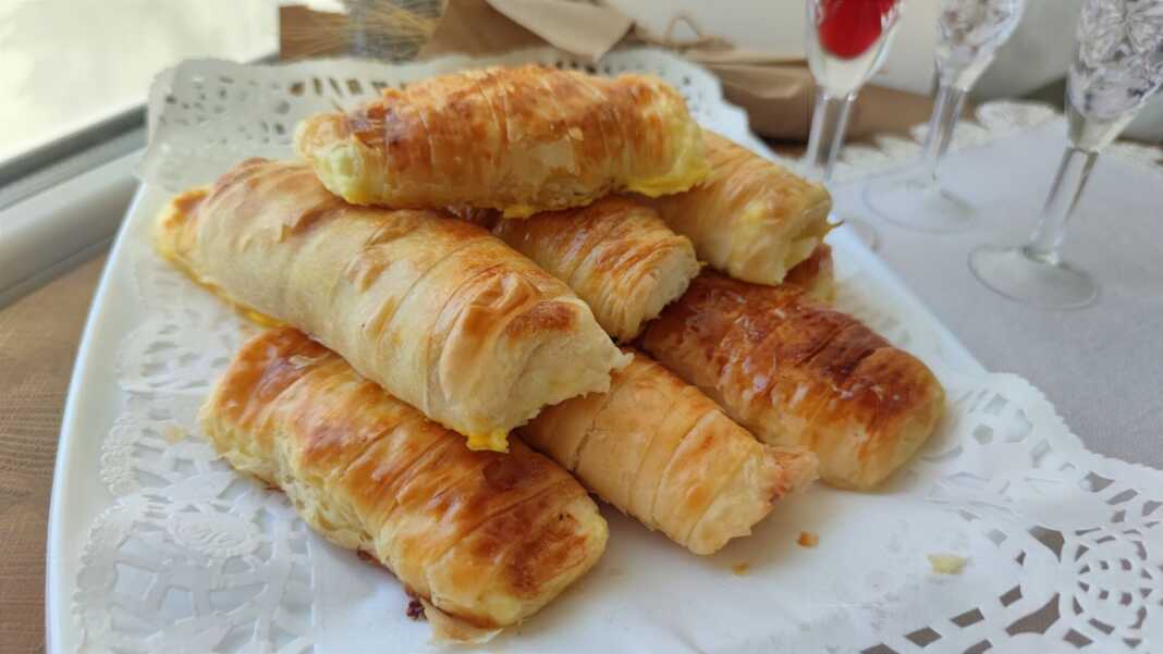 rolakiaTiropita Ένα ταψί γεμάτο με χρυσαφένια, ρολαριστά τυροπιτάκια, με ορατή τη γέμιση φέτας σε μερικά.