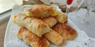 Ένα ταψί γεμάτο με χρυσαφένια, ρολαριστά τυροπιτάκια, με ορατή τη γέμιση φέτας σε μερικά.