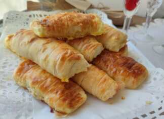 Ένα ταψί γεμάτο με χρυσαφένια, ρολαριστά τυροπιτάκια, με ορατή τη γέμιση φέτας σε μερικά.