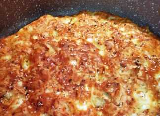 Χρυσαφένια και αφράτη τεμπέλικη τυρόπιτα μέσα σε ταψί με διάσπαρτους σπόρους στην επιφάνεια