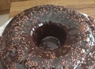 Ένα πλούσιο σοκολατένιο κέικ με γυαλιστερό γλάσο κουβερτούρας κομμένο σε κομμάτι που αποκαλύπτει τη ζουμερή και σκούρα εσωτερική του υφή