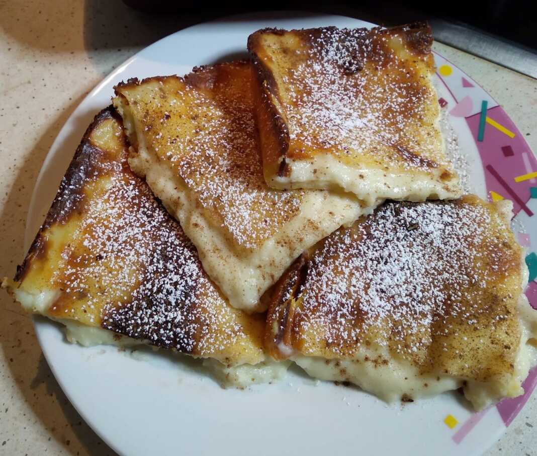 Γαλατόπιτα χωρίς φύλλο, ψημένη, πασπαλισμένη με κανέλα και ζάχαρη άχνη.