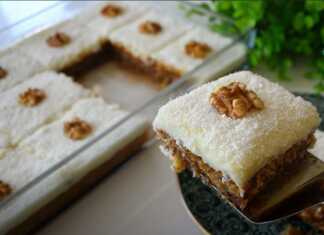 Ένα κομμάτι σιροπιαστού γλυκού με μια στρώση σαν κέικ από κάτω, μια παχιά στρώση λευκής κρέμας στη μέση και πασπαλισμένο με άφθονη τριμμένη καρύδα στην κορυφή.