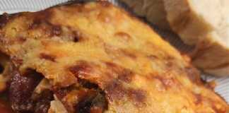 Κοντινό πλάνο σε μια μερίδα από τις μελιτζάνες στο φούρνο, που αναδεικνύει τις στρώσεις των υλικών και τα κομμάτια του λουκάνικου