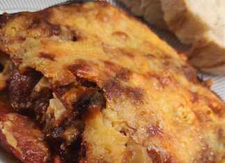 Κοντινό πλάνο σε μια μερίδα από τις μελιτζάνες στο φούρνο, που αναδεικνύει τις στρώσεις των υλικών και τα κομμάτια του λουκάνικου