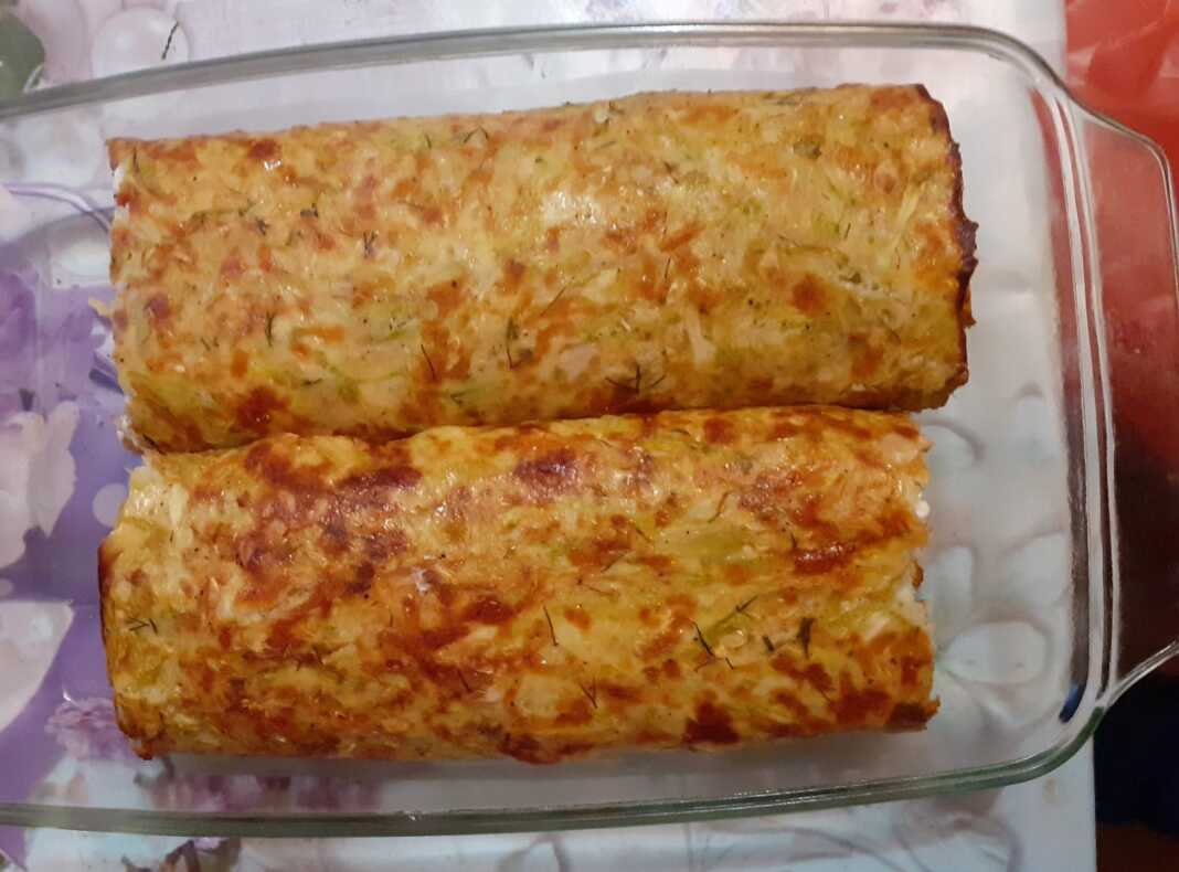 Φέτες από ένα τυλιγμένο ρολό κολοκυθιού με λευκή γέμιση τυριού κρέμας και ροζ φέτες ζαμπόν.