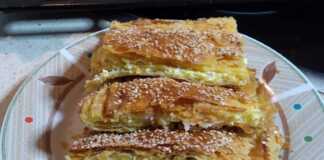 Και μια τυρόπιτα με σφολιάτα Μια χρυσαφένια, φρεσκοψημένη τυρόπιτα με σφολιάτα, κομμένη σε τετράγωνα κομμάτια, με εμφανή την τραγανή της υφή και την πλούσια γέμιση τυριού.