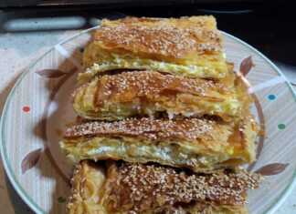 Μια χρυσαφένια, φρεσκοψημένη τυρόπιτα με σφολιάτα, κομμένη σε τετράγωνα κομμάτια, με εμφανή την τραγανή της υφή και την πλούσια γέμιση τυριού.