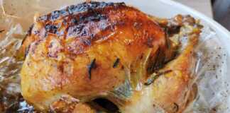 Ολόκληρο ροδοκοκκινισμένο κοτόπουλο μόλις βγει από τη σακούλα ψησίματος περιχυμένο με τους ζωμούς του και φρέσκα μυρωδικά