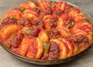 Ταψί με κεφτέδες, πατάτες και πιπεριές, περιχυμένα με σάλτσα ντομάτας, έτοιμα για ψήσιμο στο φούρνο.