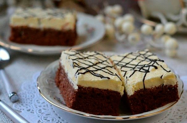 keikKremagiaourtiou Ένα κομμάτι κέικ με μια λευκή, παχιά στρώση κρέμας γιαουρτιού στην κορυφή, σερβιρισμένο σε ένα λευκό πιάτο.