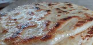 Λαδωμένο ταψί γεμάτο με χρυσαφένιες, στρογγυλές πίτες που μοιάζουν με σαλιγκάρια, ψημένες, με λιωμένο τυρί να φαίνεται σε σημεία.