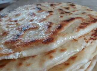 Λαδωμένο ταψί γεμάτο με χρυσαφένιες, στρογγυλές πίτες που μοιάζουν με σαλιγκάρια, ψημένες, με λιωμένο τυρί να φαίνεται σε σημεία.